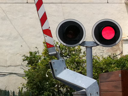 En un paso a nivel, ¿qué indican dos luces rojas alternativamente intermitentes?