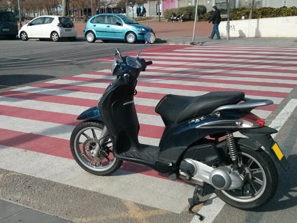 Este ciclomotor está invadiendo la marca vial de paso para peatones, ¿es correcto este estacionamiento?